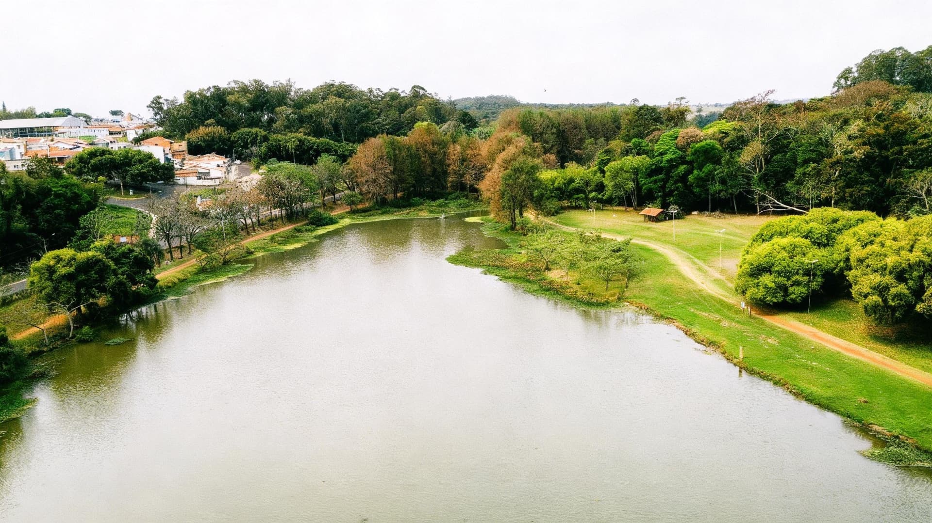 Grande lago contornado por árvores e grama verde