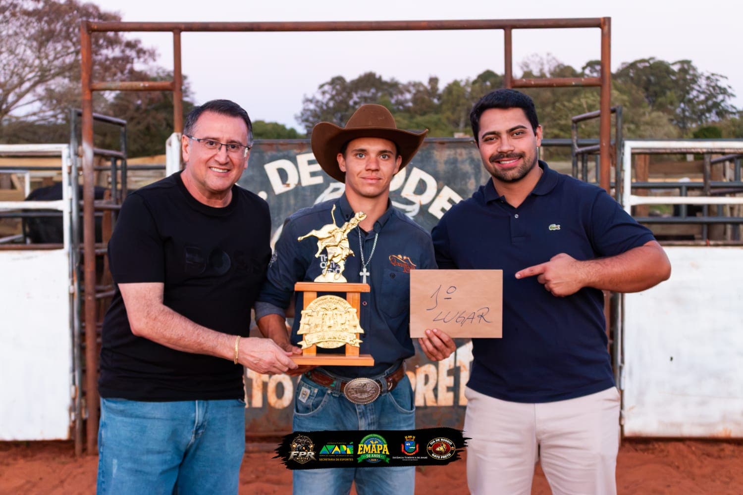 Descrição da imagem / #PraCegoVer: Patrick Nascimento aparece ao centro usando chapéu de peão e segurando o troféu e a identificação de 1º lugar da seletiva na modalidade cutiano. Ao lado dele estão dois homens que participaram da premiação. Ao fundo, há a estrutura da arena de rodeio no bairro rural da Ponte Alta, em Avaré.