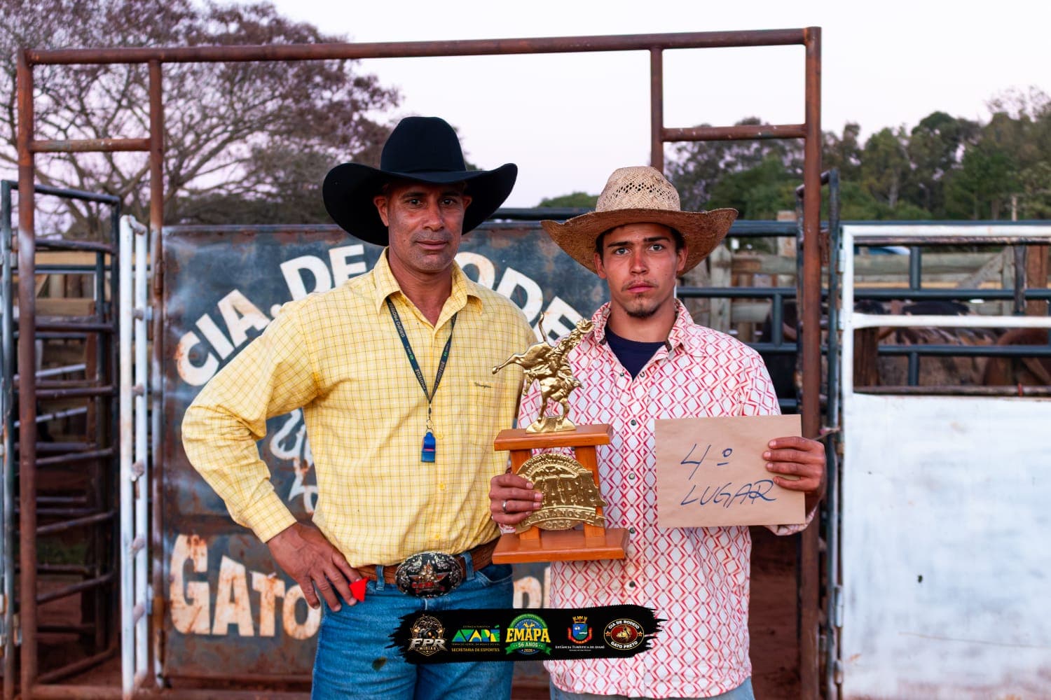 Gustavo Vieira, quarto colocado na seletiva da modalidade cutiano, aparece segurando o troféu e uma placa com a indicação de 4º lugar. Ao lado dele está um integrante da organização. Ambos usam chapéu e posam diante da estrutura da arena de rodeio no bairro rural da Ponte Alta, em Avaré.